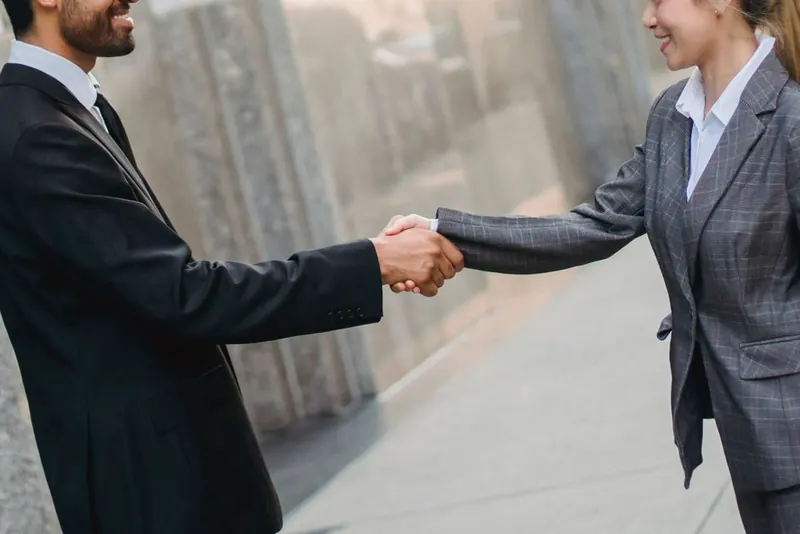 Two people shaking hands outdoors after agreeing shared driveway work