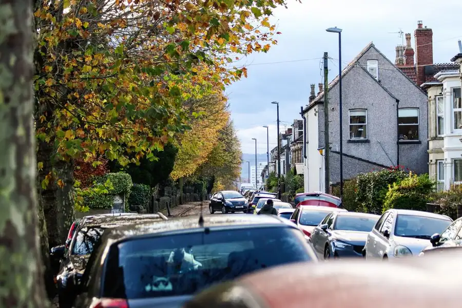 Autumn leaves falling on a British residential street, the seasonal debris that drives driveway cleaning frequency in Swindon