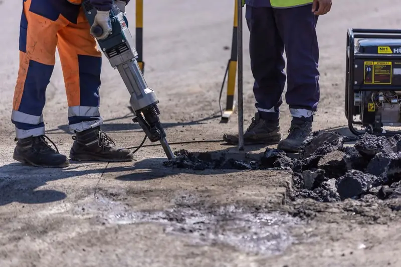 Breaking up an old tarmac surface with a breaker before laying a new resin bound driveway