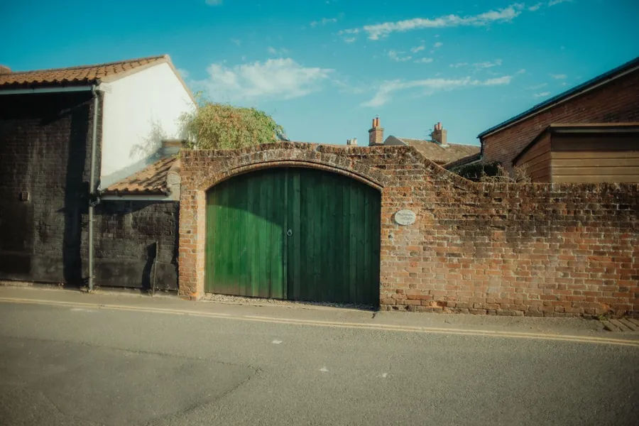 Brick boundary wall and timber gates at a property entrance, the sort of external structure buildings insurance treats separately from the house
