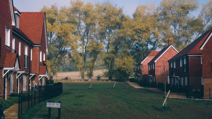 Brick houses with small front gardens around a green on an estate, where front gardens are often turned into driveways