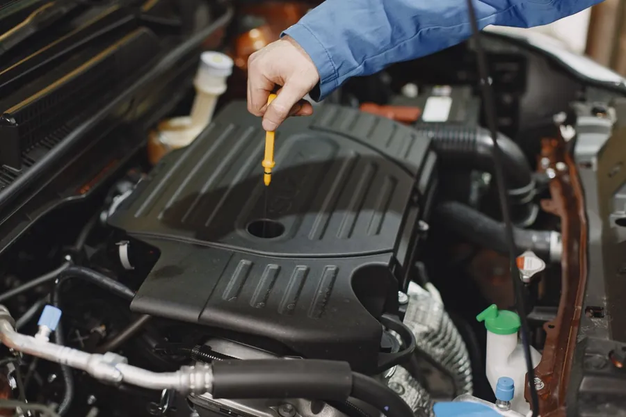 Checking engine oil on a car, a common source of the spills that damage driveway surfaces in Swindon