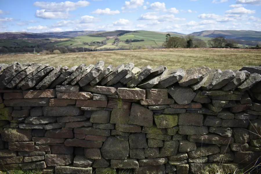 Dry stone wall built from flat limestone pieces across Cotswold farmland, the same brash found under many Cirencester driveways