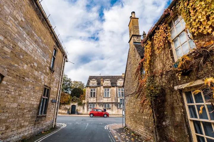 Cotswold stone houses along a quiet street, the kind of older property where resin driveway costs in Cirencester depend on access