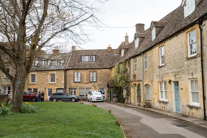 Cars parked along the kerb outside a terrace of Cotswold stone houses, a common parking problem behind dropped kerb requests in Cirencester