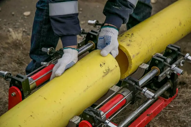 Yellow ducting being installed in an open trench before a driveway sub-base is laid