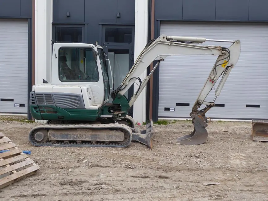 Compact excavator cutting a level formation on a sloping site