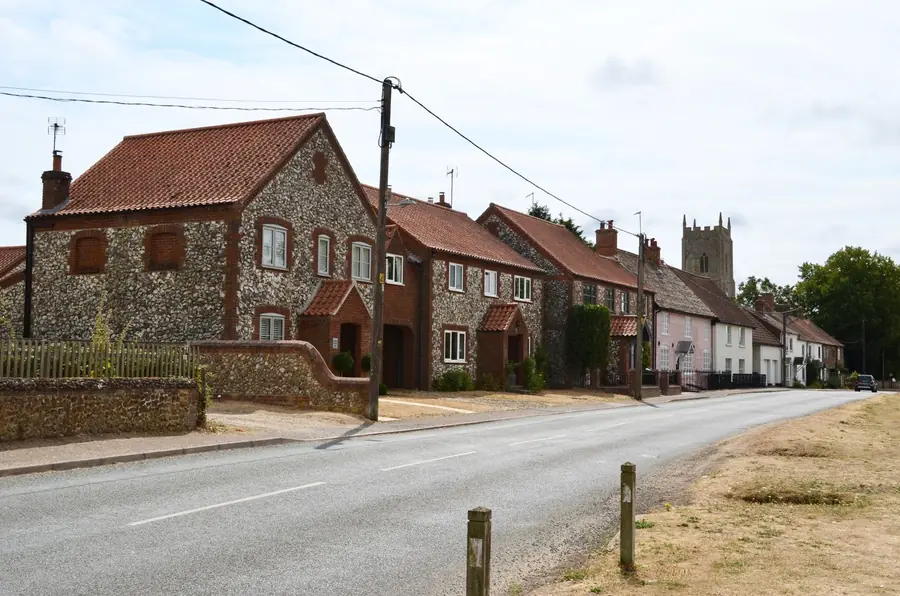 Row of flint and brick cottages along a village road, the building stone dug from ground like Marlborough's clay-with-flints