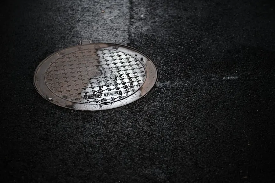 Cast iron inspection cover set into a wet surface on a residential street