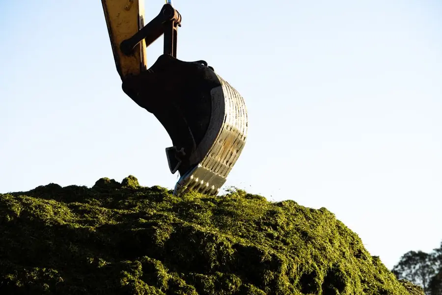 Excavator bucket lifting disturbed soil on a building plot