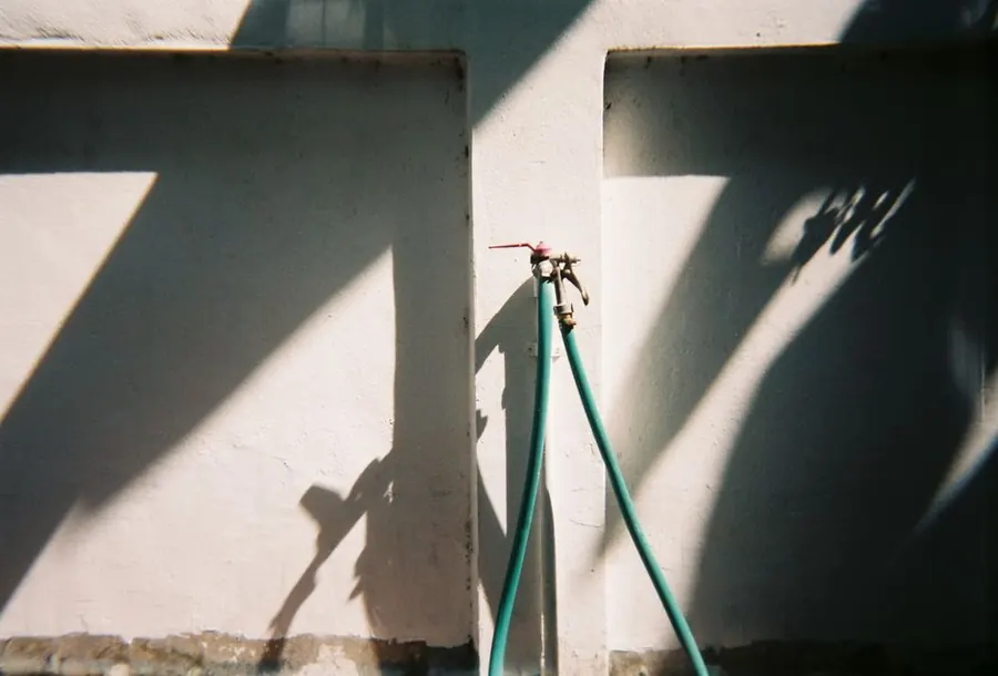 Outside tap and hose fitted to an exterior wall beside a driveway