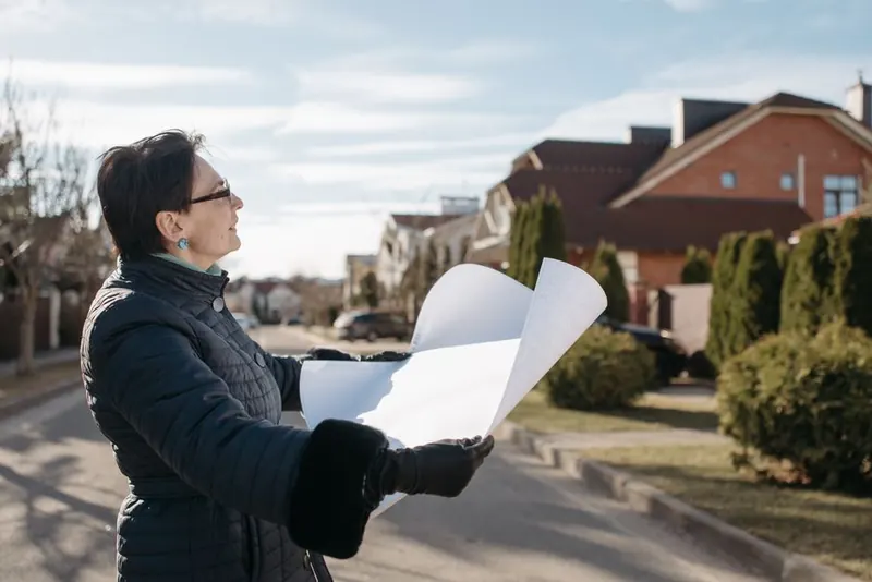 Person reviewing plans outdoors before starting a driveway conversion project