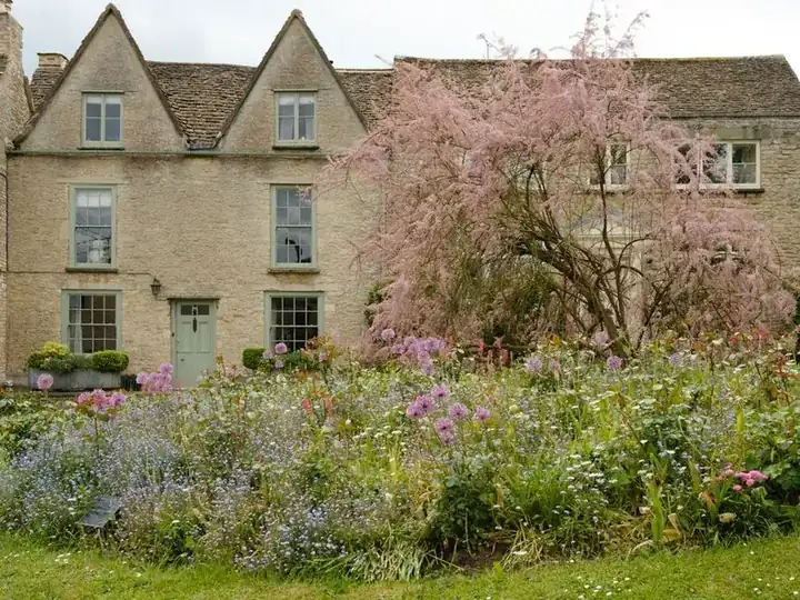 Stone cottage with a densely planted front garden border, showing planting kept alongside hard surfacing