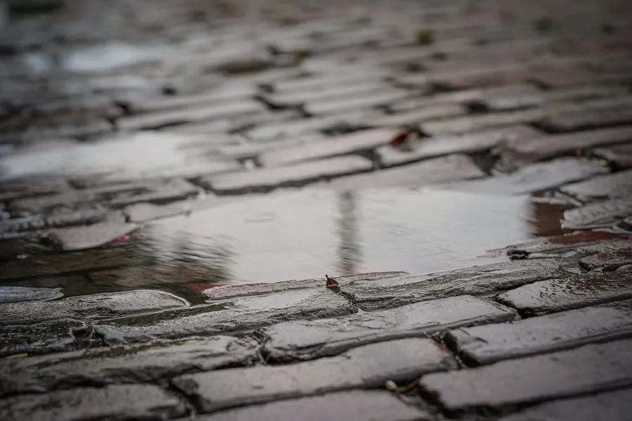 Rain soaking into a wet brick-paved surface, showing why a permeable driveway matters on clay ground in Royal Wootton Bassett