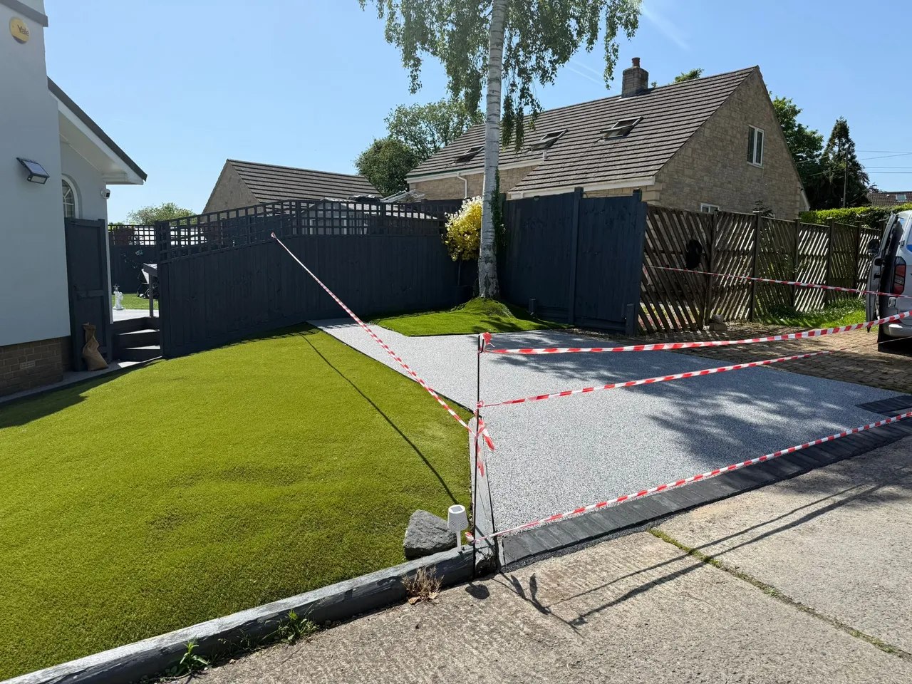 Smart grey resin bound driveway with artificial grass border at a Swindon property, freshly completed