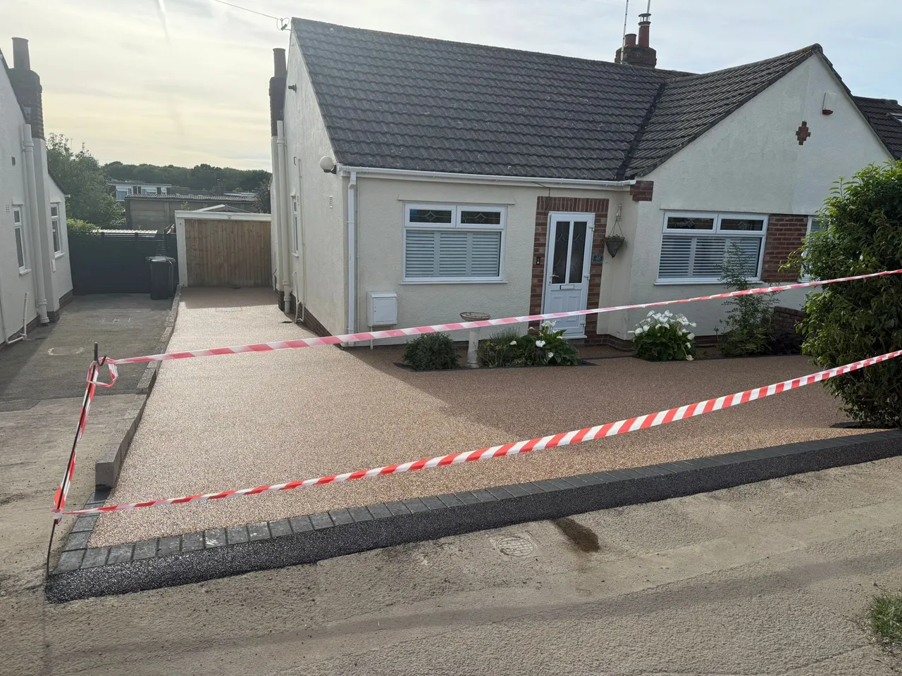 Freshly installed buff resin bound driveway at a bungalow in Swindon, safety tape up while it cures