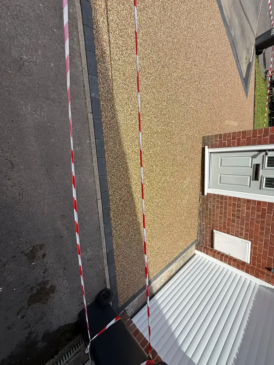 Aerial view of a freshly installed buff resin bound driveway with block paving border at a Swindon property, safety tape still in place