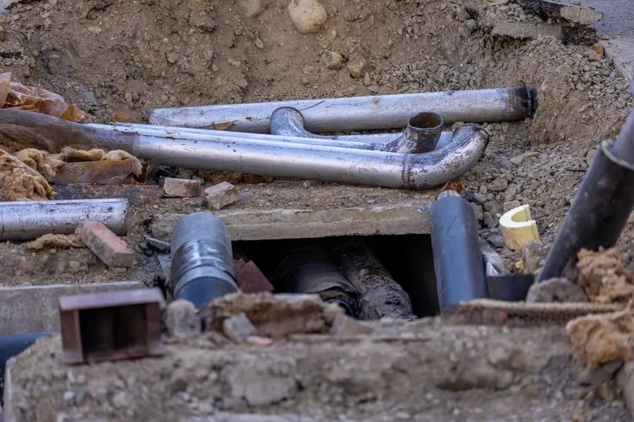 Service pipes and ducts exposed in a trench before a driveway is laid