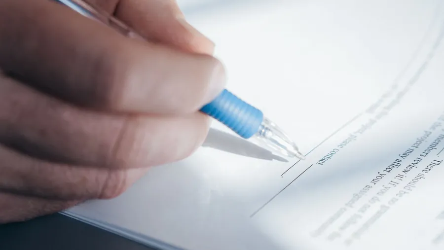 Hand signing tenancy paperwork with a pen, the inventory record that decides driveway damage claims on a Swindon rental