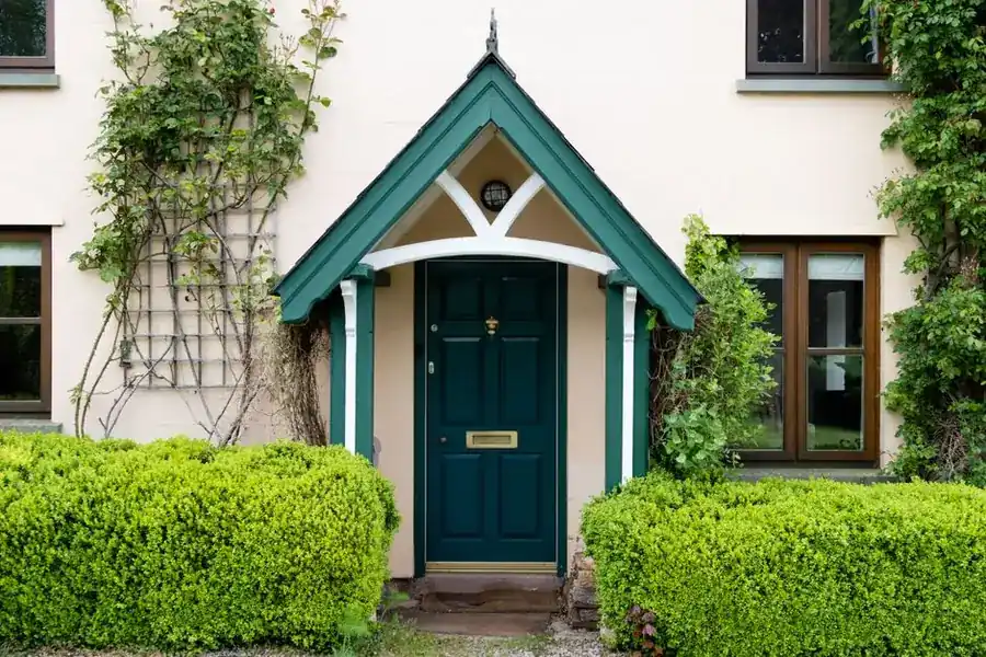 Narrow front entrance and path to an English house with clipped hedging