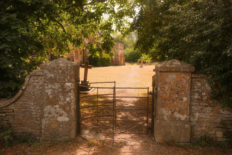 Old Cotswold stone gate piers opening onto a loose gravel drive, the traditional look many Cirencester homeowners replace with resin