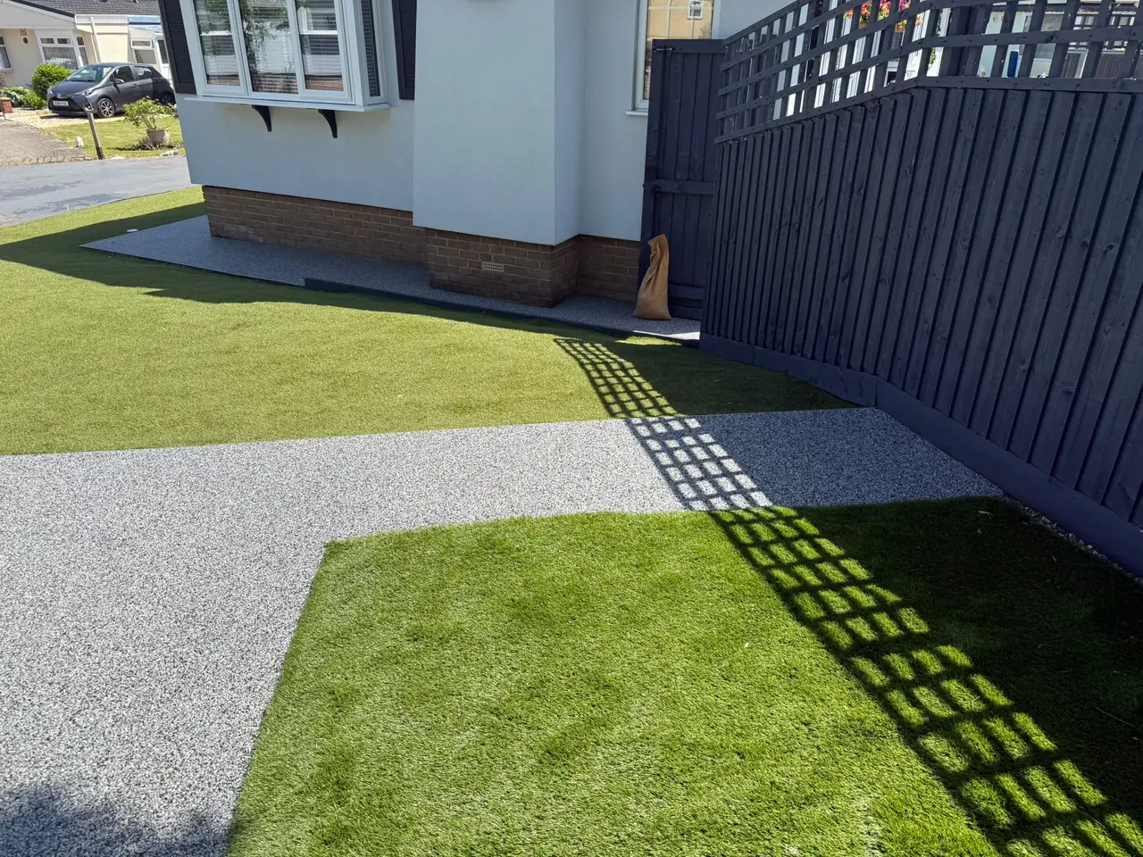 Finished grey resin driveway with artificial grass border after installation in Swindon